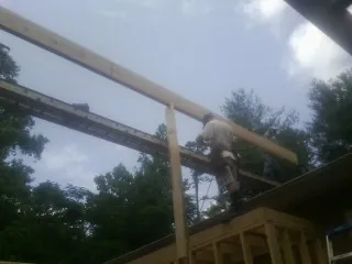 Carpenter setting a ridge beam over a new addition frame — Ice Dam Removal by Roofing Brothers in Mc Alpin