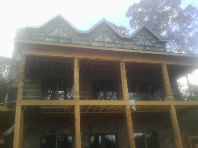Dormers and porch framing on a large log home under construction — Roof Coating work by our crew in Mc Alpin