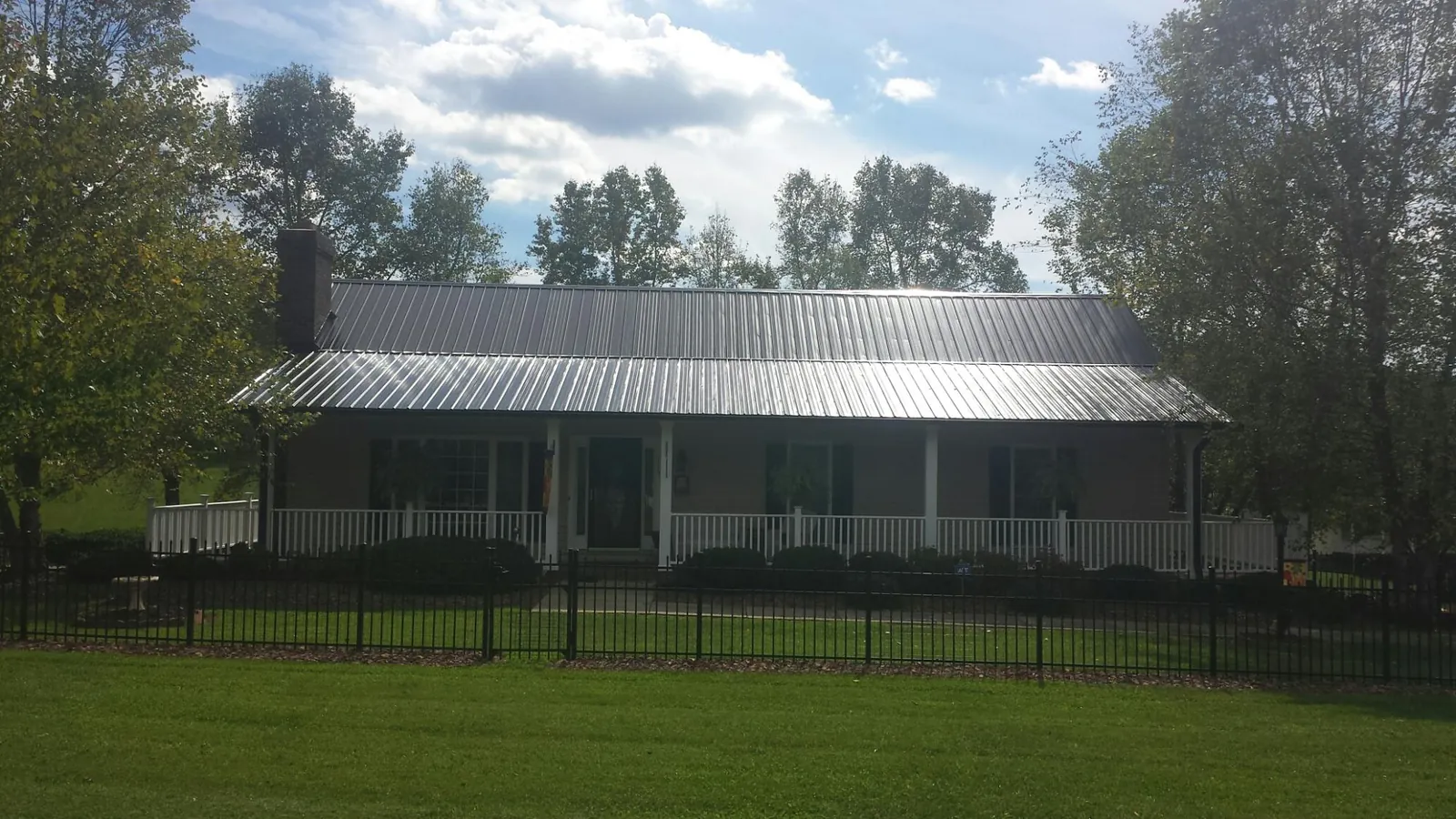 Gray metal roof on a brick ranch with a full width front porch — Gutter Guard Installation work by our crew in Mc Alpin