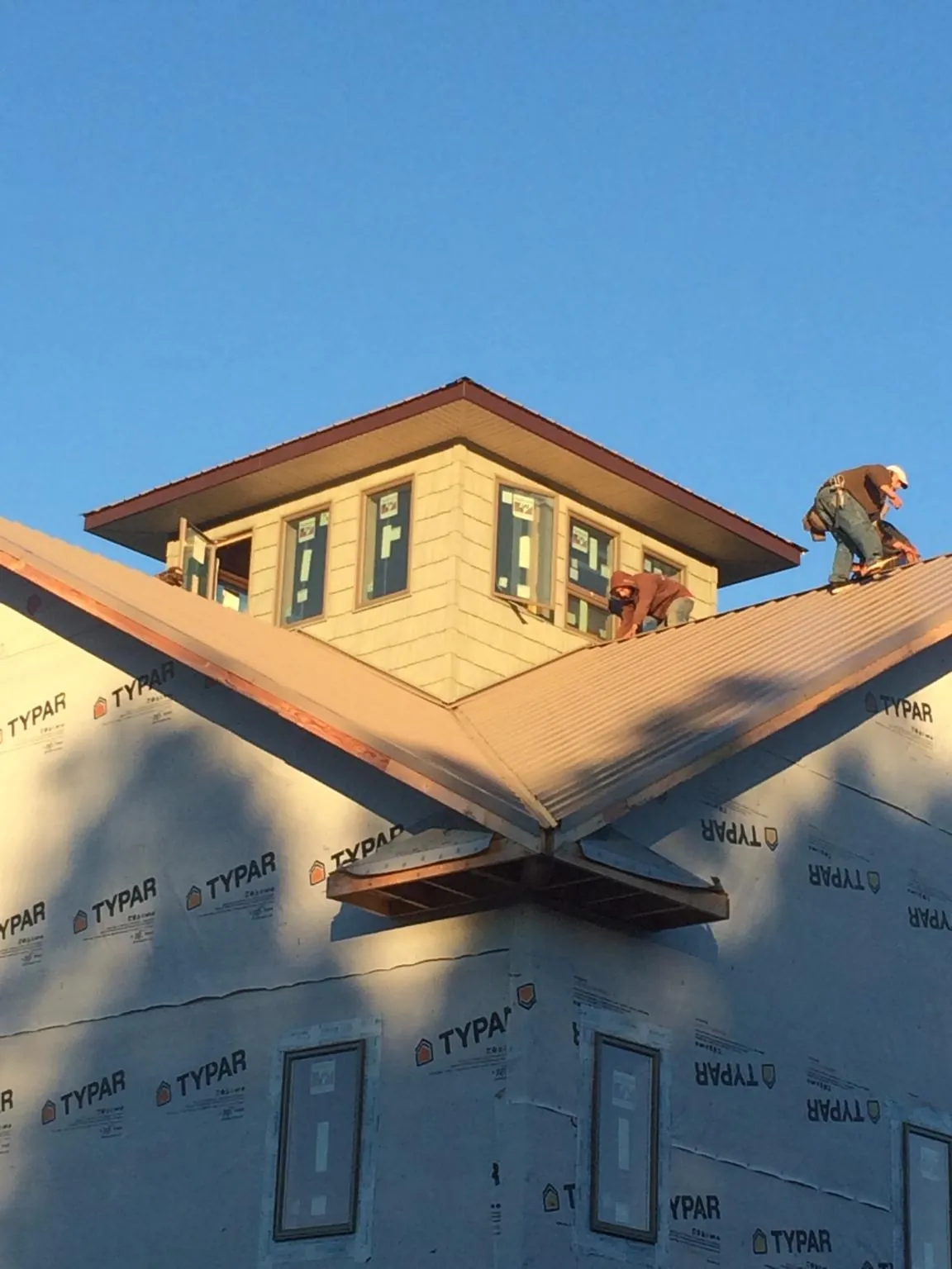 Roofers working around a rooftop cupola on a new metal roof at sunset — Roof Waterproofing in Mc Alpin by Roofing Brothers